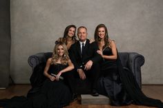 a group of people sitting on top of a couch in front of a gray wall