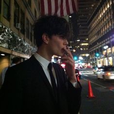 a man talking on a cell phone while standing in front of a building at night