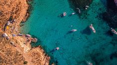 an aerial view of several boats in the water near some cliffs and sand beached shorelines