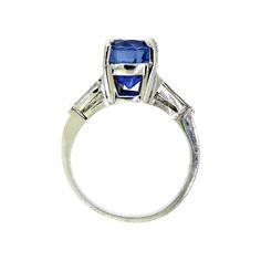 The sapphire in this vintage-style platinum mounting is the most incredible blue. The mixed cut oval is a strongly saturated, violetish blue with a medium dark tone, and moderately included clarity. It's easy to get lost in the deep blue sparkle set off by two tapered baguette diamonds on each side. The platinum mounting is a very sturdy, yet still elegant rendition of the 1940s style. It will stack beautifully with a curved baguette band, or be just as lovely on its own. It's also a nice choice Classic Oval Sapphire Ring With Polished Finish, Classic Blue Sapphire Ring, Classic Sapphire Ring With Baguette Cut, Classic Blue Sapphire Ring In Platinum, Timeless Baguette-cut Sapphire Ring, Classic Baguette Cut Sapphire Ring, Vintage Blue Sapphire Ring In Platinum, Classic Blue Sapphire Gemstone Ring, Vintage Blue Oval Sapphire Ring