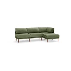 a green sectional couch sitting on top of a white floor next to a wooden frame