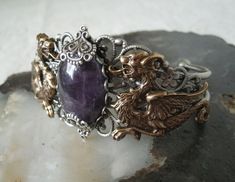 This beautiful silver plated filigree cuff bracelet has antique brass dragons, silver plated accents and an amethyst setting. Adjustable. Medieval Style Metal Jewelry For Fantasy Events, Medieval Style Silver Jewelry With Intricate Design, Fantasy Engraved Jewelry For Fantasy Events, Gold Medieval Jewelry For Themed Events, Medieval Gold Jewelry For Fantasy Events, Elegant Silver Jewelry For Fantasy Events, Medieval Handmade Cuff Bracelet As A Gift, Handmade Medieval Cuff Bracelet As Gift, Handmade Medieval Cuff Bracelet For Gifting