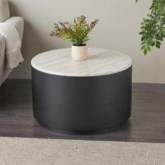 a white and black table with a potted plant on it next to a couch