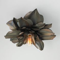 a light that is hanging from the ceiling with flowers on it's sides and leaves in the middle