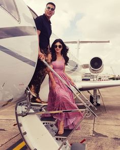 a man and woman standing on the steps of an airplane