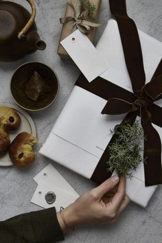 a person holding a piece of paper with a brown ribbon on it next to other items