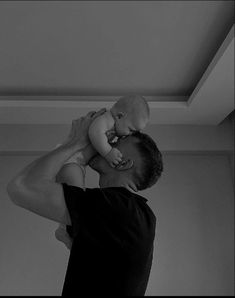 a man holding a baby up to his face while he holds it in the air