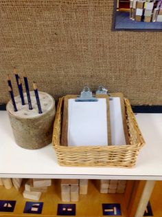 a basket with pencils and paper on top of a table next to a wooden block