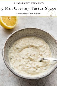 a white bowl filled with creamy tartar sauce next to an orange slice and spoon