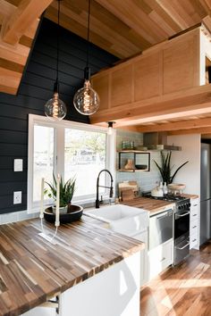 a kitchen with wood floors and black walls is pictured in this image, there are lights hanging from the ceiling