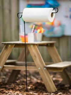 a toilet paper dispenser sitting on top of a wooden table next to a picnic table