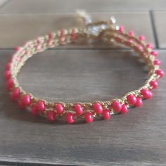 a pink beaded bracelet sitting on top of a wooden table