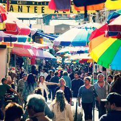 many people are walking down the street with umbrellas over their heads and in front of them