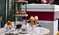 three tiered trays with ice cream cones and desserts on them sitting on a table