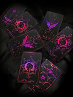 four glowing playing cards on a black surface with pink and purple lighting in the middle