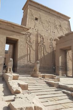 the entrance to an ancient egyptian temple with statues on it's walls and steps