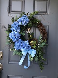 a wreath with blue flowers is hanging on the front door