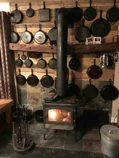 an old fashioned stove with pots and pans on the wall behind it in a rustic kitchen