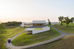 an aerial view of a modern house in the middle of a grassy area with a car parked on the driveway