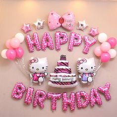 a hello kitty birthday cake surrounded by balloons and helium letters that spell out the word, happy birthday