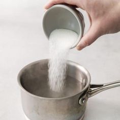 a person is pouring sugar into a saucepan