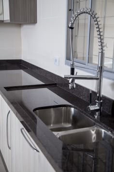 a kitchen with black granite counter tops and white cupboards next to a stainless steel sink