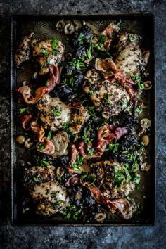 chicken with mushrooms, olives and parsley in a black pan on a table