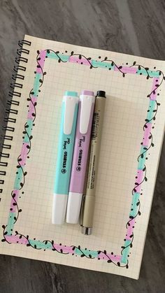 two pens sitting next to each other on top of a notepad with an empty notebook