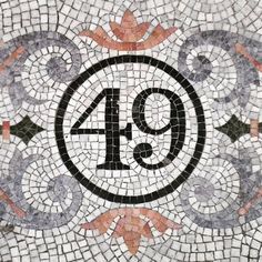 the number forty nine is depicted on a mosaic tile wall with an ornamental design in black and white