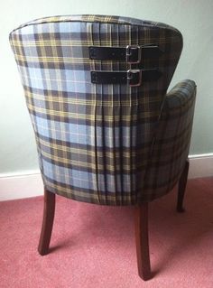 a plaid chair sitting on top of a pink carpeted floor next to a wall