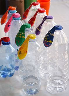 several plastic water bottles are lined up on the table with colorful spoons in them