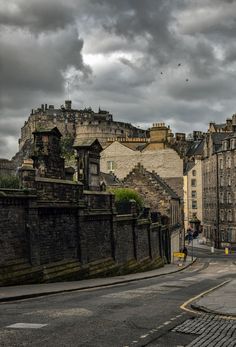 an old city street with cobblestones and stone buildings on both sides under a cloudy sky