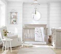 a baby's room with white walls and wooden furniture, including a crib