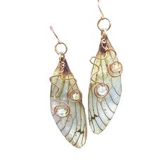 Ethereal Fairy Wing Earrings Delicate and magical are the only way to describe these pretty Cicada wing earrings. A 2 inch long wing with a drop of 2.25 inches, they dangle so lightly being made from translucent plastic. They are so light you won't even know you are wearing them! A touch of sparkle is added to the wing with holographic glitter that gives a special touch of magic to the fairy earrings. Two crystals that match the color of the wing dance upon copper wire swirls that give that spec Cute Fairy Earrings, Cheap Whimsical Metal Jewelry, Fantasy Accessories Earrings, Cicada Wing Earrings, Whimsical Cheap Metal Jewelry, Fae Wings, Earrings Wing, Wire Swirls, Fairy Wing Earrings