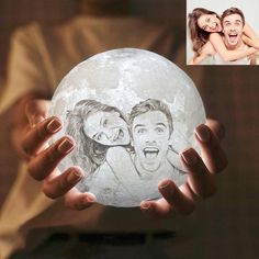 a person holding up a white moon with an image of two people on it in front of them