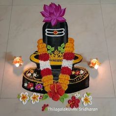 a decorated idol sitting on top of a white tiled floor next to candles and flowers