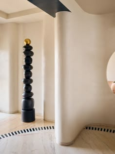 a tall black and gold sculpture sitting in the middle of a room next to a mirror