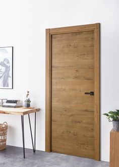 a wooden door in a white room next to a table with a potted plant