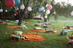 an outdoor picnic with lots of food and decorations on the grass in front of a tree