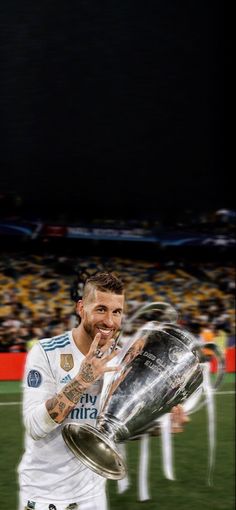 a man holding a soccer trophy in front of his face while standing on a field