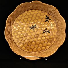 a yellow plate with two black bees on the front and one is in the middle