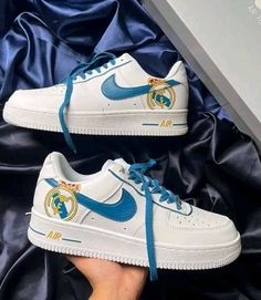 someone is holding their white nike air force sneakers with blue and gold details on them