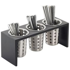 three metal cups with spoons in them on a black shelf against a white background