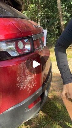 a woman is standing next to a red car with the hood up and it's door open