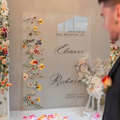 a man standing in front of a sign with flowers on it and confetti