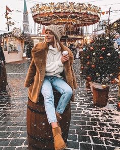 a woman sitting on top of a barrel in the snow