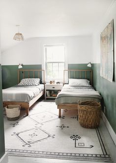 two beds in a room with green walls and rugs on the floor next to each other