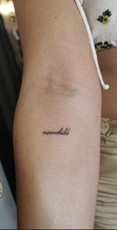 a woman's arm with the word moonchild tattooed on her left arm, in black ink