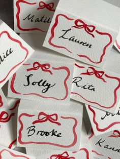 several name tags with bows on them are shown in red and white paper, which reads