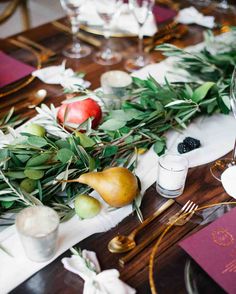 the table is set with fruit and greenery for a festive dinner or reception